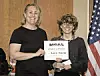 Two individuals at a recognition ceremony holding a certificate.