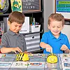 Two boys playing with coding robots in a classroom setting.