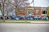 Crowd of people in blue shirts in front of a building.