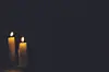 Two candles burning in a dark setting.