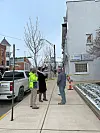 Three people talking on a sidewalk near a building.