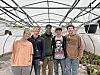 Five individuals standing in a greenhouse.