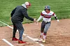 Softball player high-fiving coach at home plate.