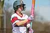 Female athlete holding a bat in a softball game.