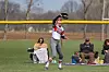 Softball player catching a ball with spectators in the background.