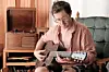 Musician playing guitar in a vintage room.