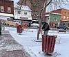 Worker cutting a pole on a sidewalk in a small town.