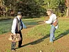 Two people in a reenactment scene in a forested area.