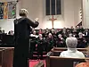 Choir performing in a church with a conductor leading.