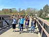 Group of people with arms raised on a bridge.