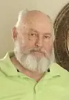 Man with a beard wearing a green shirt indoors.