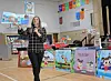 Speaker holding a book in a school gym with colorful displays.