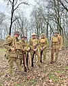 Group of reenactors in World War I uniforms in a forest.