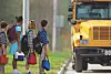 Children waiting for a school bus on the roadside.