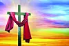 Wooden cross with red fabric against a colorful sunset.