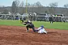 Softball player diving for a catch with another player sliding into base.