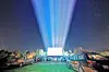 Cars at an outdoor movie screening with a bright screen.