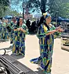Women in colorful dresses dancing at an outdoor event.
