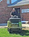 Man operating a lawn care machine on grass.
