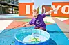 Child in purple shirt playing next to a small water pool.