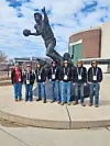 Students standing by a basketball statue outdoors.