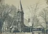 Historic church building with a steeple and surrounding trees.