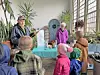 Children listening to instructors in a greenhouse setting.
