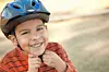 Smiling boy in a blue helmet outdoors.