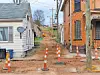 Residential street with construction cones and machinery.