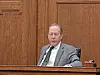 Man sitting in a courtroom with wooden walls.