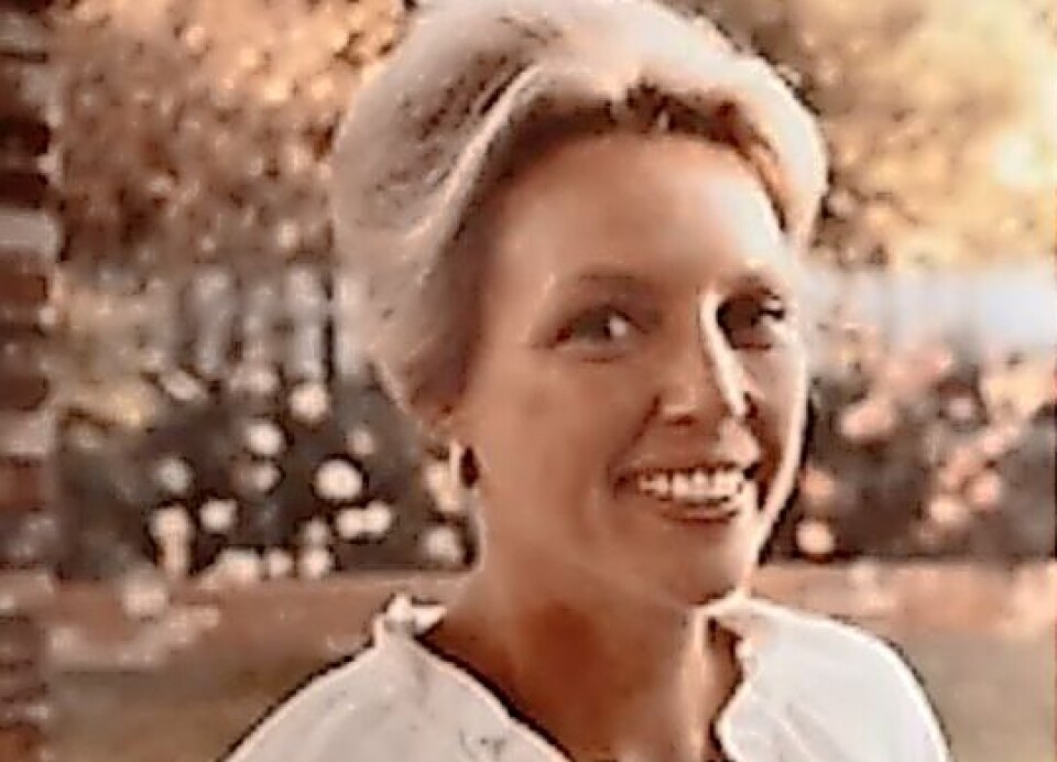 Woman smiling outdoors with light-colored hair.