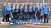 Softball team in blue and black uniforms poses together on the field.