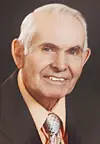 Elderly man in a suit smiling at the camera.