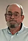 Man with glasses and beard in a light blue shirt.