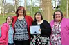 Four women pose outdoors holding a certificate.