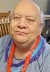 Individual with gray hair wearing colorful leis.