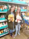 Two people holding plush toys in a store aisle.