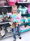 Girl with plush toys in a store aisle.