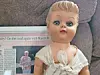 Vintage doll with a newspaper article behind it.