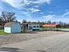 Mobile home and shed in a rural setting under a blue sky.