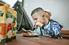A boy eating at a picnic table with juice boxes in view.