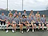 High school tennis team posing together on a court.