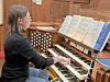 Musician at an organ with sheet music in a church.