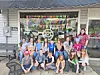 Group of children and adults outside a decorated shop.