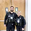 Two police officers in uniform smiling together.