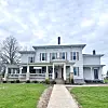 Historic white house with porch and green lawn.