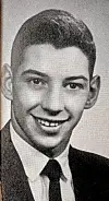 Young man in a suit smiling in a black-and-white portrait.