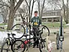 A boy poses with multiple bicycles in a driveway.