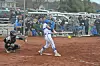 Softball player swings at a pitch with a catcher behind.