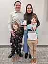 Family holding an award in a neutral background.